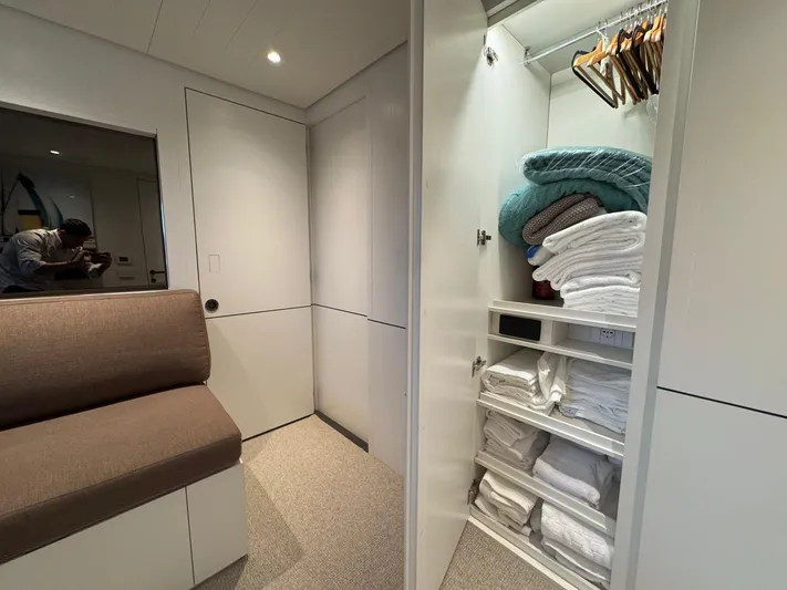  Yacht Photos Pics 2022 Bluegame BGX70 yacht interior with open closet, towels, and seating area.