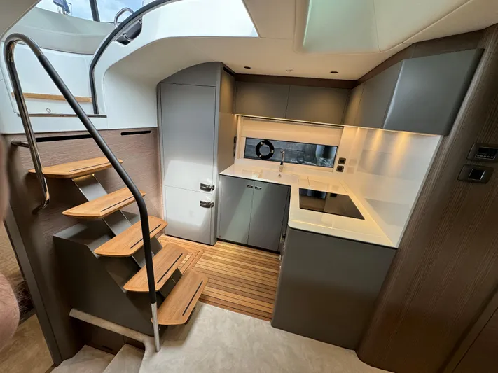  Yacht Photos Pics Modern kitchen interior of 2023 Princess V50 Open yacht with sleek cabinetry and wooden stairs.