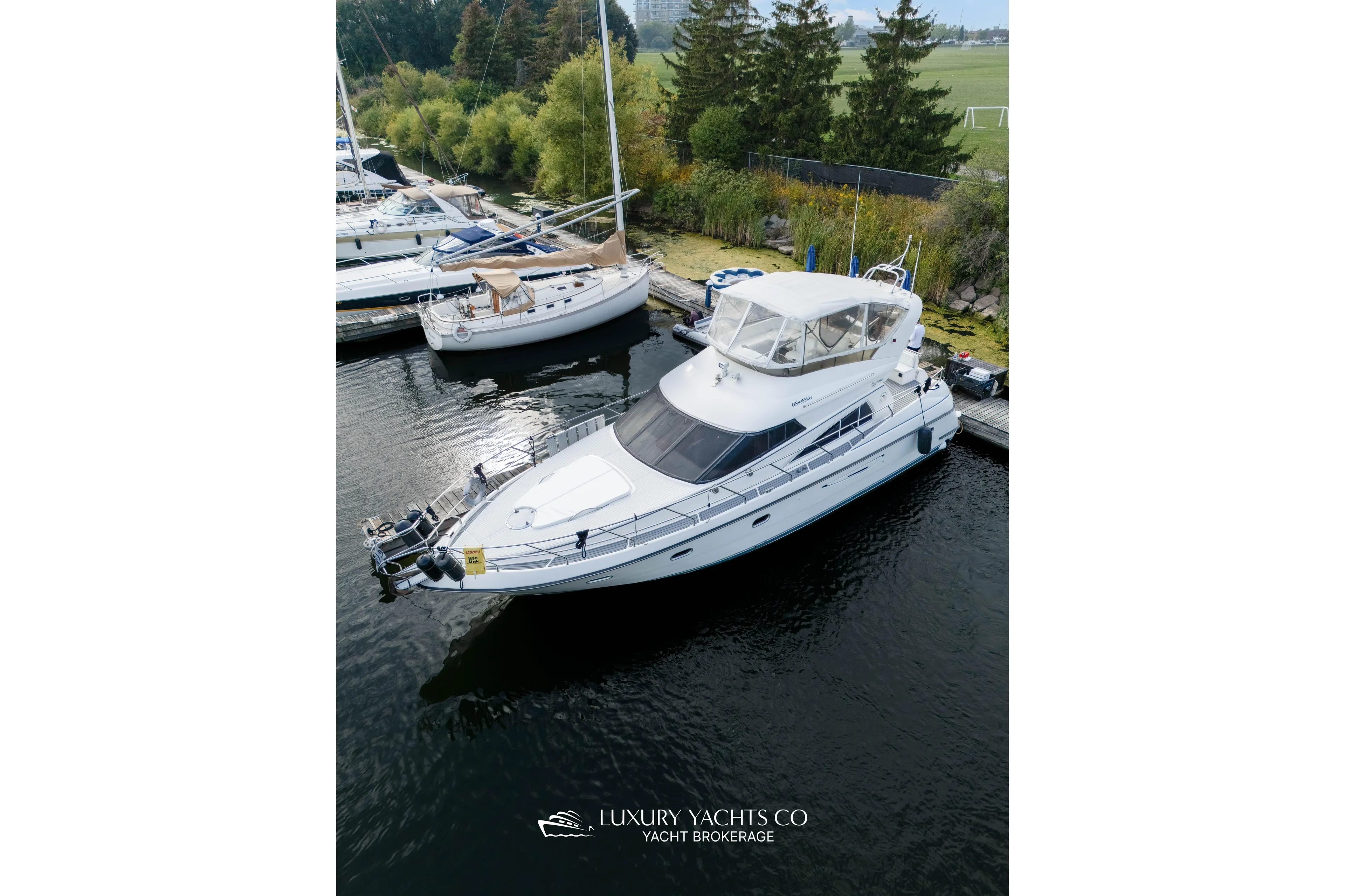  Yacht Photos Pics 1997 Neptunus 50 Aft Cabin yacht docked at marina, surrounded by trees and other boats.