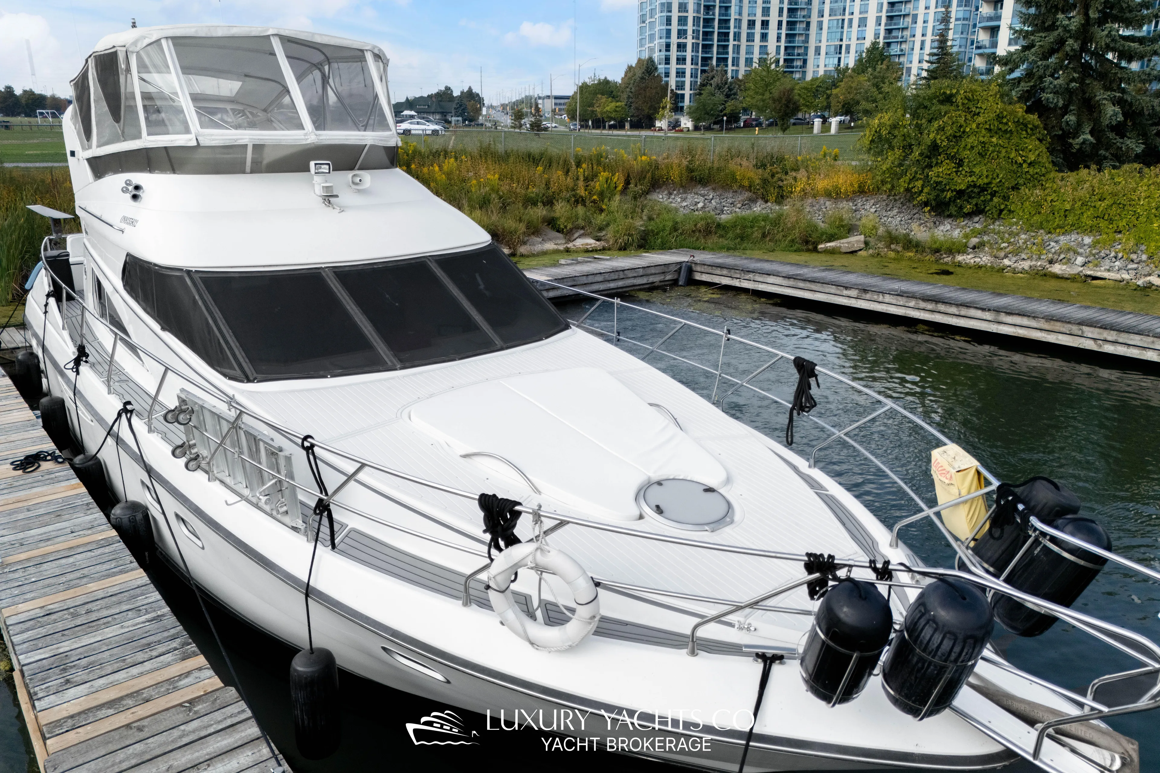  Yacht Photos Pics 1997 Neptunus 50 Aft Cabin yacht docked at marina, surrounded by greenery.