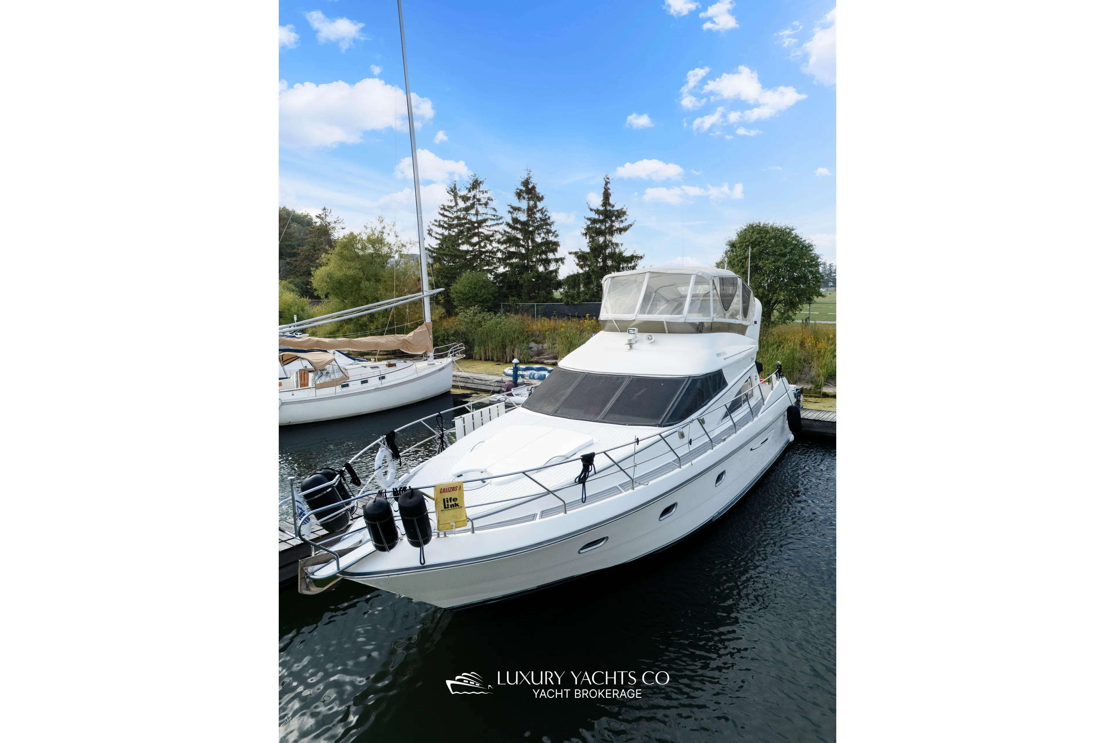  Yacht Photos Pics 1997 Neptunus 50 Aft Cabin yacht docked, clear sky, lush greenery background.