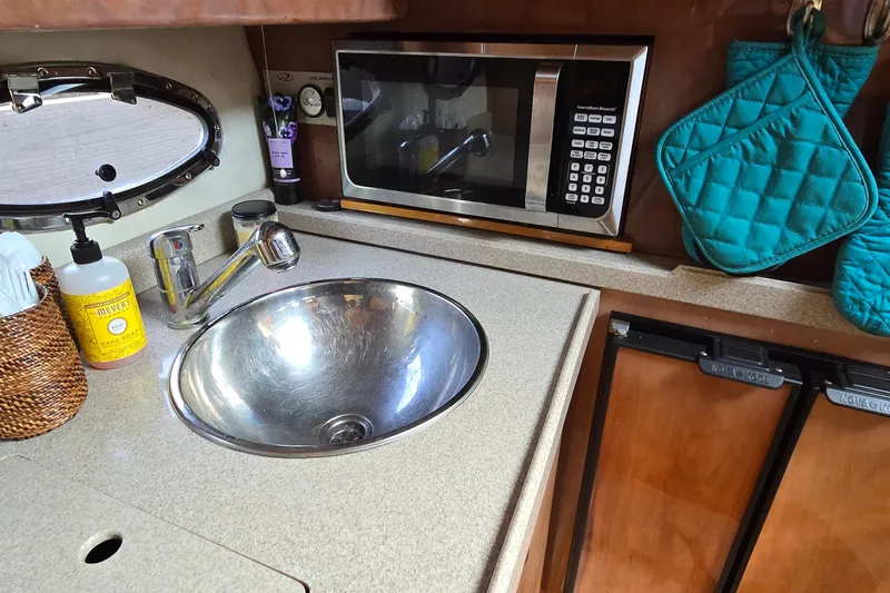 Yacht Photos Pics 2003 Regal Commodore 4260 yacht kitchen with sink, microwave, and teal oven mitts.