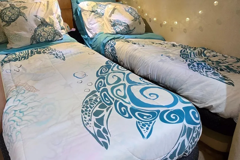  Yacht Photos Pics Twin beds with turtle-themed bedding in a cozy cabin setting.