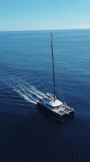 Kajikia Yacht Photos Pics Aerial view of 2023 Lagoon 77 catamaran sailing on open sea.