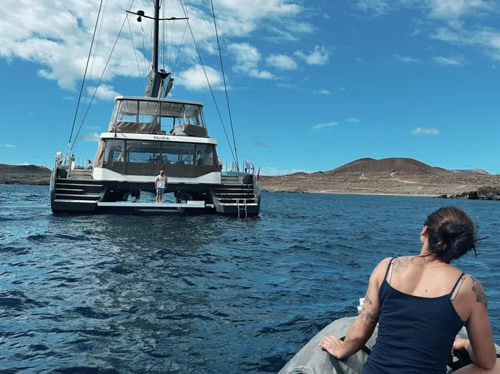 Kajikia Yacht Photos Pics Person approaching Lagoon 77 yacht on a small boat in open water, 2023.
