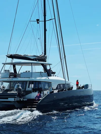 Kajikia Yacht Photos Pics 2023 Lagoon 77 yacht sailing on open sea under clear blue sky.