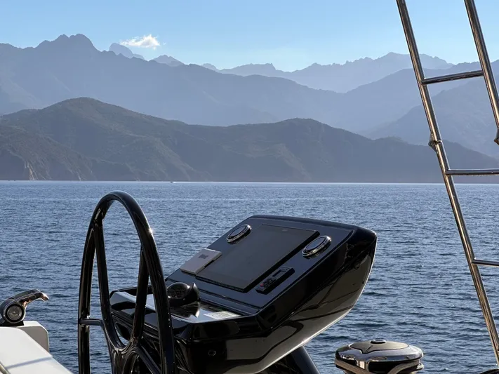 Kajikia Yacht Photos Pics Helm of 2023 Lagoon 77 yacht with scenic mountain and sea view.