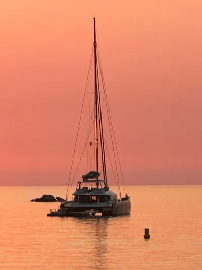 Kajikia Yacht Photos Pics Lagoon 77 catamaran at sunset, 2023 model, on calm waters with pink sky.