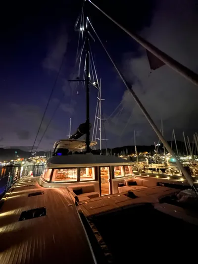 Kajikia Yacht Photos Pics 2023 Lagoon 77 yacht illuminated at night in a marina setting.