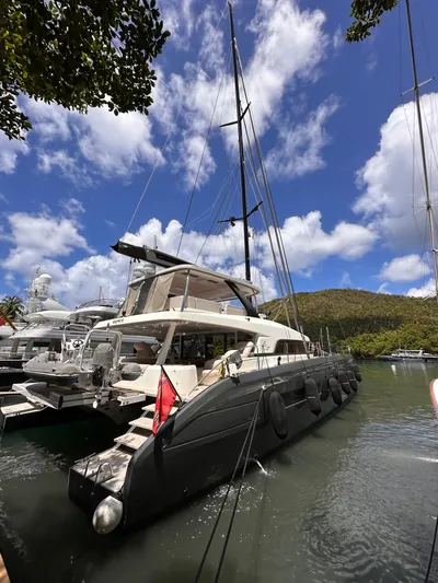 Kajikia Yacht Photos Pics 2023 Lagoon 77 yacht docked in a scenic marina under a blue sky.