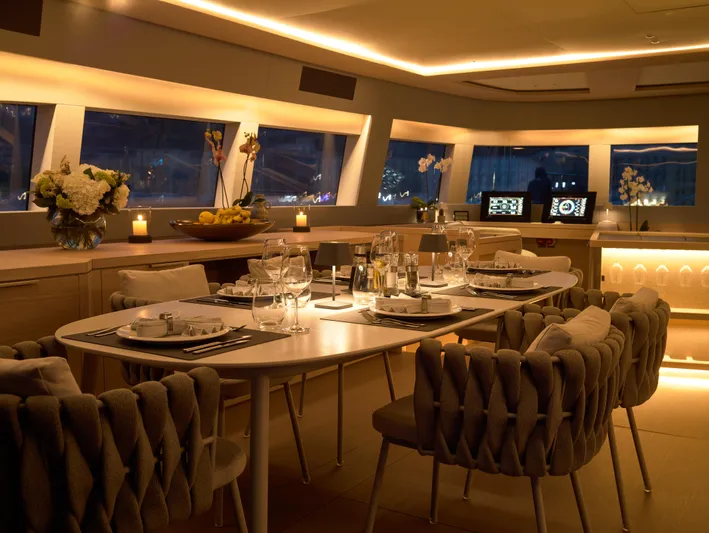 Kajikia Yacht Photos Pics Luxurious dining area inside 2023 Lagoon 77 yacht, elegantly set with ambient lighting.