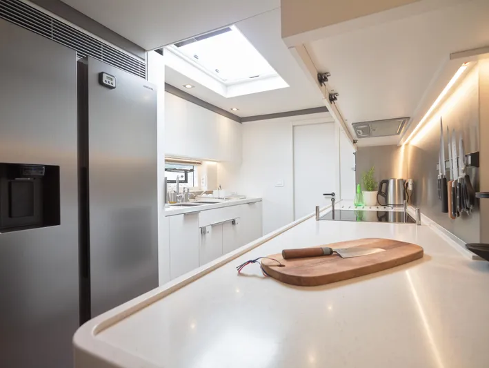 Kajikia Yacht Photos Pics Modern kitchen interior on 2023 Lagoon 77 yacht, featuring sleek design and stainless steel appliances.