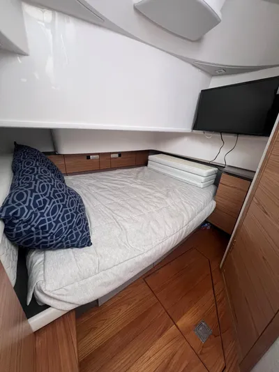  Yacht Photos Pics 2023 Tiara Yachts 38 LS cabin interior with bed, TV, and wooden flooring.