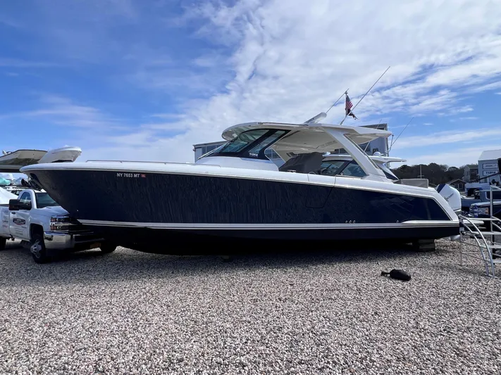  Yacht Photos Pics 2023 Tiara Yachts 38 LS, sleek design, docked on gravel, under a partly cloudy sky.