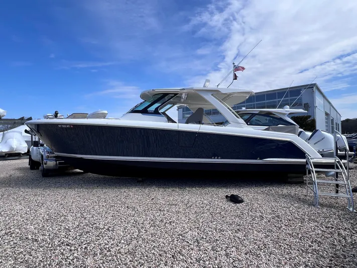  Yacht Photos Pics 2023 Tiara Yachts 38 LS boat on gravel, with blue hull and white top.