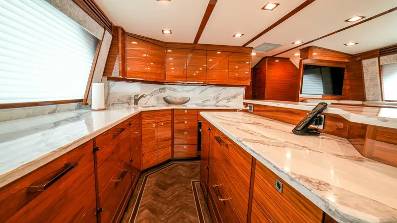 Free Spool Yacht Photos Pics Luxurious kitchen interior of 2023 Viking 72 yacht with wooden cabinets and marble countertops.