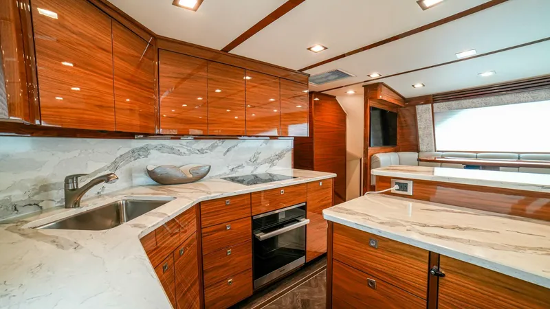 Free Spool Yacht Photos Pics Luxurious kitchen interior of 2023 Viking 72 yacht with wood cabinetry and marble countertops.