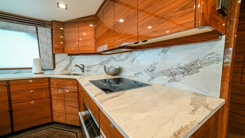 Free Spool Yacht Photos Pics Luxurious kitchen in 2023 Viking 72 yacht with marble countertops and sleek wooden cabinetry.