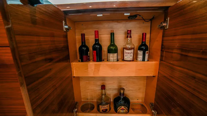 Free Spool Yacht Photos Pics Wooden cabinet with assorted liquor bottles on a Viking 72 yacht, 2023 model.