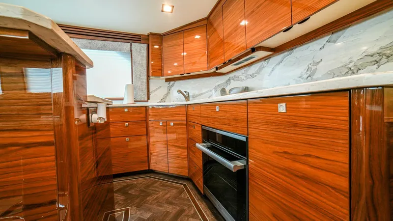 Free Spool Yacht Photos Pics Luxurious kitchen interior of 2023 Viking 72 yacht with wood cabinetry and marble countertops.