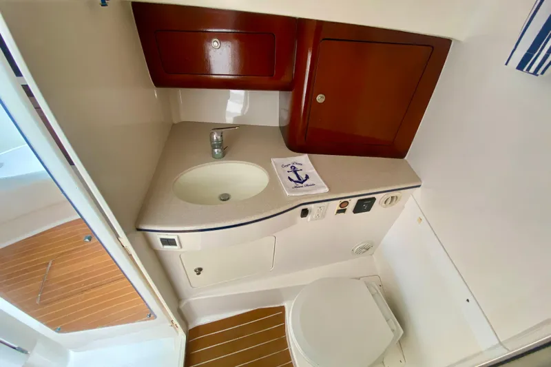  Yacht Photos Pics 2000 Intrepid 377 Walkaround boat bathroom with sink, toilet, and wooden cabinets.