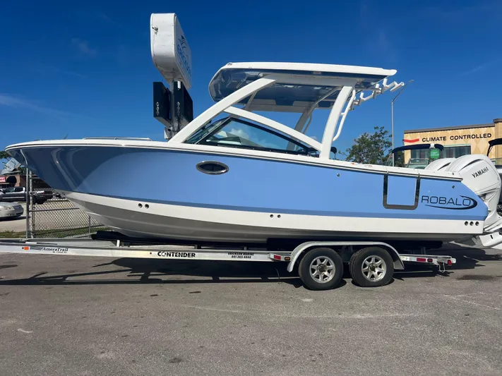  Yacht Photos Pics 2025 Robalo R257 Dual Console boat on trailer, blue and white design, parked outdoors.