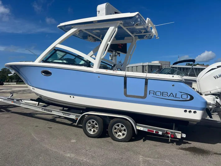  Yacht Photos Pics 2025 Robalo R257 Dual Console boat on trailer, blue and white design, parked outdoors.