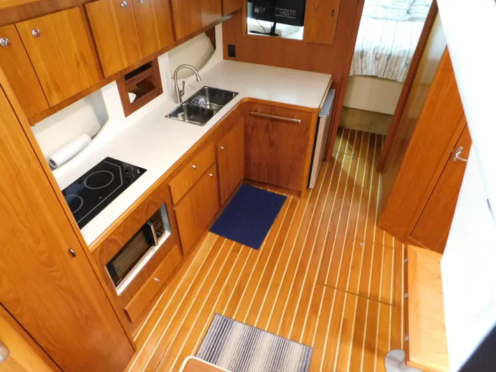 Sun Baked Yacht Photos Pics 1999 Tiara Yachts 3500 Express galley with wood cabinetry, sink, stove, and microwave.