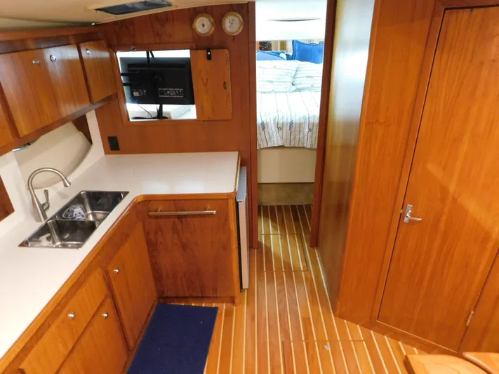 Sun Baked Yacht Photos Pics 1999 Tiara Yachts 3500 Express interior with wood cabinetry, sink, and cozy bedroom.