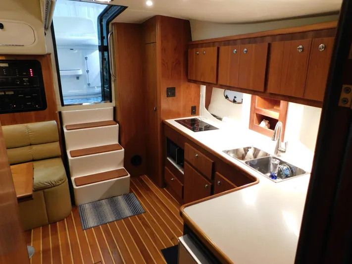 Sun Baked Yacht Photos Pics 1999 Tiara Yachts 3500 Express interior with kitchen, stairs, and seating area.