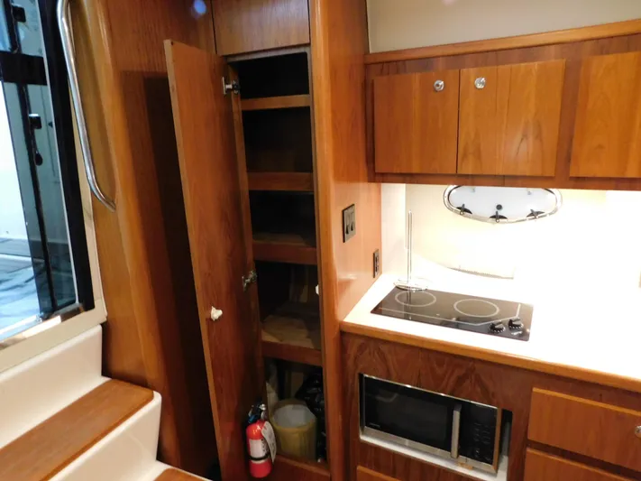 Sun Baked Yacht Photos Pics 1999 Tiara Yachts 3500 Express interior kitchen with stove, microwave, and wooden cabinets.