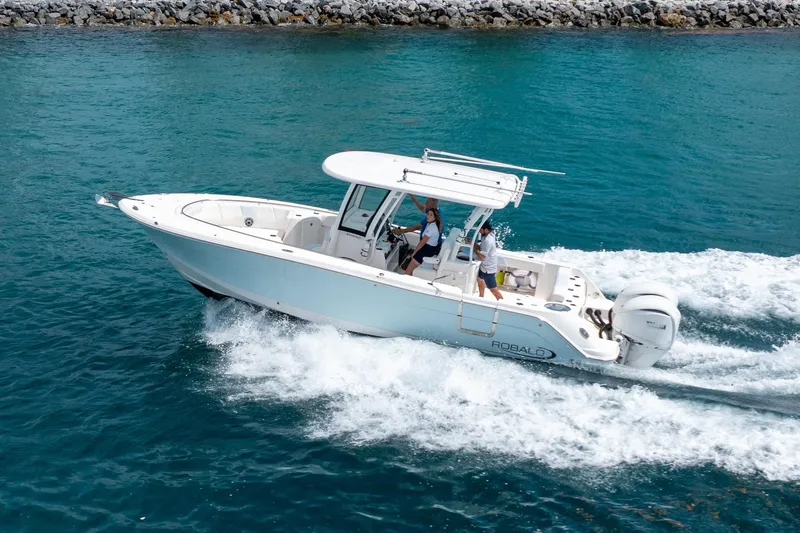  Yacht Photos Pics 2023 Robalo R302 Center Console boat cruising on clear blue water.