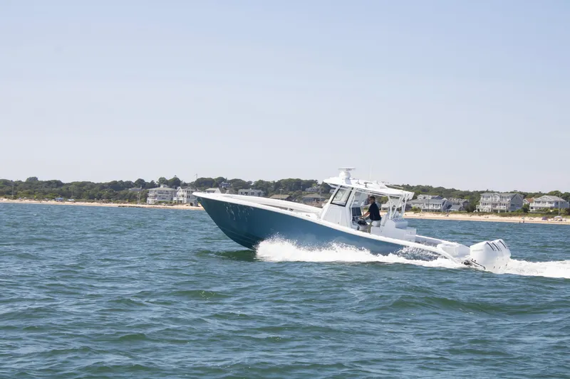  Yacht Photos Pics 2026 Yellowfin 36 Offshore boat cruising near coastal homes on a sunny day.