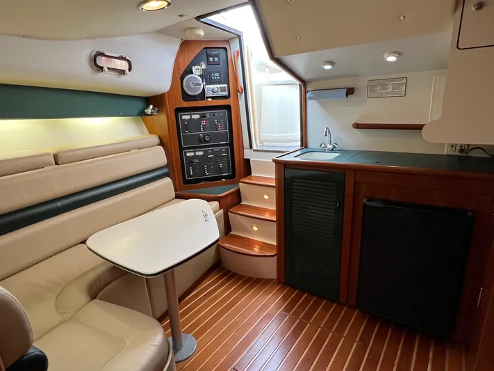  Yacht Photos Pics 1998 Pursuit 3400 Offshore DIESEL cabin interior with seating, table, and kitchenette.