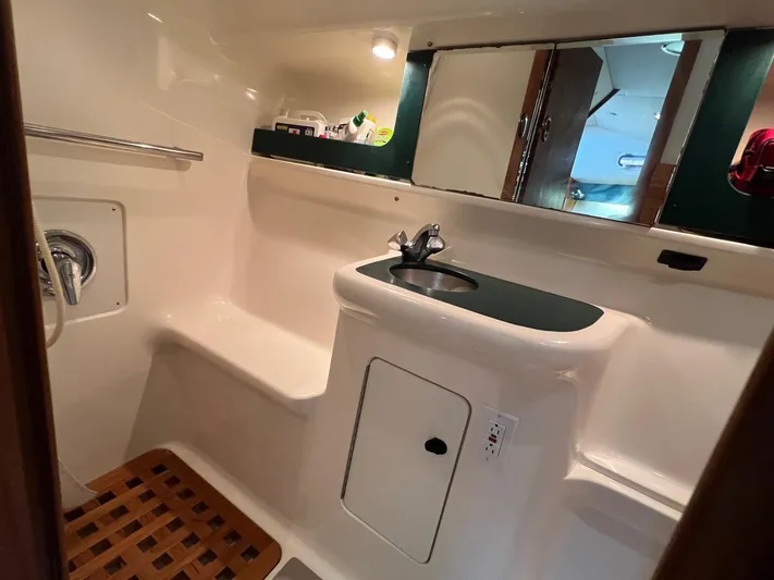  Yacht Photos Pics 1998 Pursuit 3400 Offshore DIESEL boat bathroom with sink, mirror, and wooden floor mat.