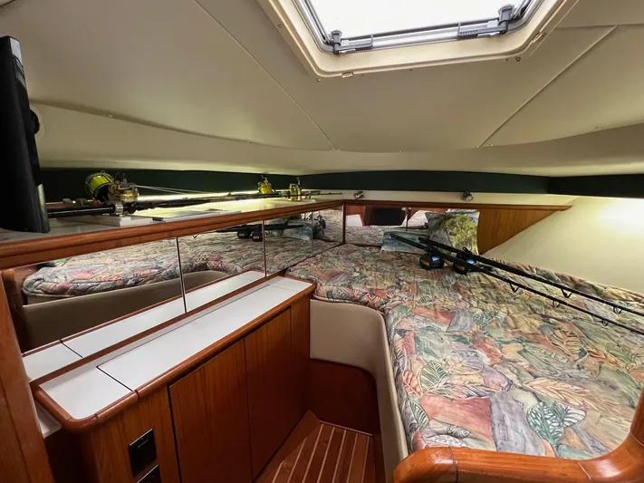  Yacht Photos Pics 1998 Pursuit 3400 Offshore DIESEL cabin interior with bed, fishing rods, and wooden cabinetry.