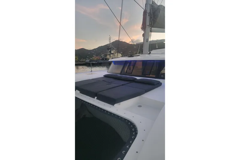 Three Sheets Yacht Photos Pics 2019 Fountaine Pajot Saona 47 catamaran at sunset, docked with mountain backdrop.