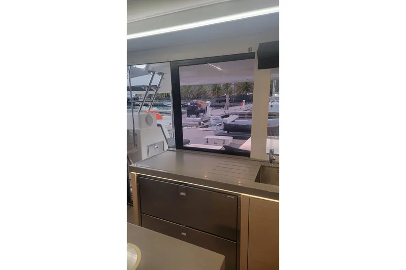 Three Sheets Yacht Photos Pics Interior view of 2019 Fountaine Pajot Saona 47 catamaran kitchen with marina backdrop.