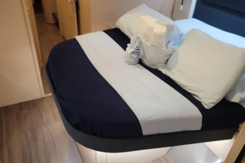 Three Sheets Yacht Photos Pics Cozy bedroom interior of 2019 Fountaine Pajot Saona 47 catamaran with neatly arranged bed linens.