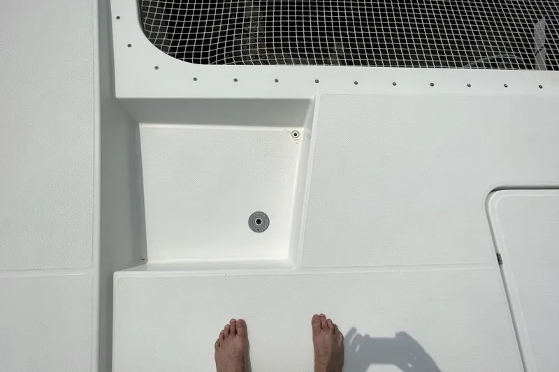 Three Sheets Yacht Photos Pics Deck of 2019 Fountaine Pajot Saona 47 catamaran with netting and feet visible.