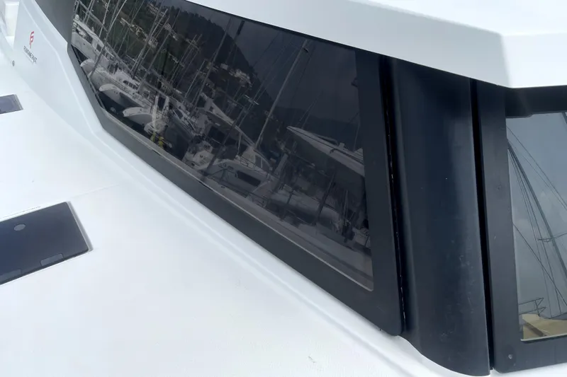 Three Sheets Yacht Photos Pics Close-up of 2019 Fountaine Pajot Saona 47 yacht window reflecting marina scene.