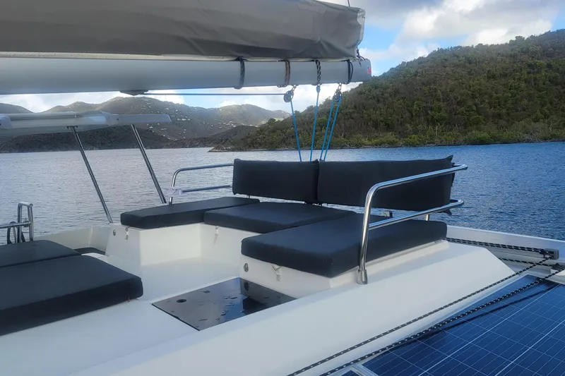 Three Sheets Yacht Photos Pics 2019 Fountaine Pajot Saona 47 catamaran with cushioned seating, anchored in scenic waters.