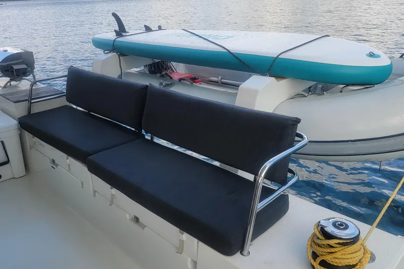 Three Sheets Yacht Photos Pics 2019 Fountaine Pajot Saona 47 yacht with black seating, paddleboard, and dinghy on deck.