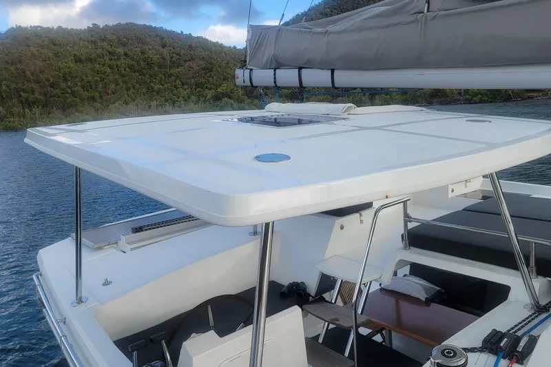 Three Sheets Yacht Photos Pics 2019 Fountaine Pajot Saona 47 catamaran with sleek deck design, anchored near lush hills.