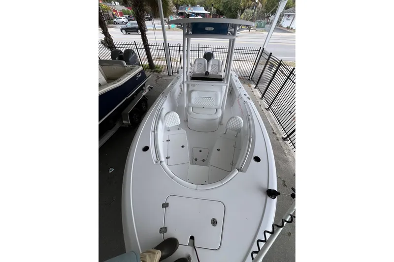  Yacht Photos Pics 2024 Sportsman Open 212 Center Console boat, white interior, parked near a fence.