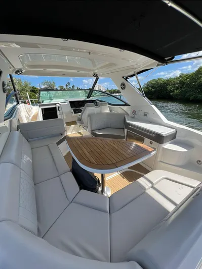 2023 Sea Ray Sundancer 320 @ Cancun Yacht Photos Pics 2023 Sea Ray Sundancer 320 interior with seating and table, docked by lush greenery.