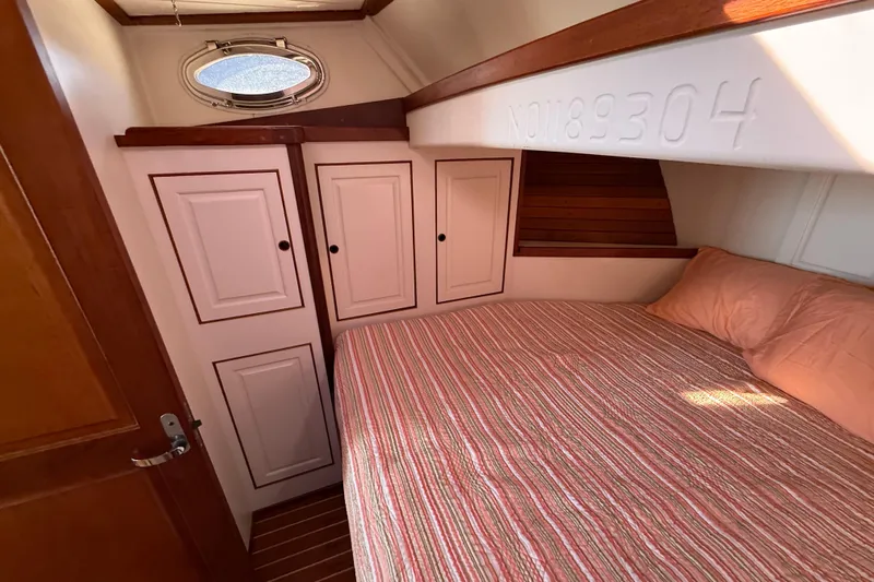  Yacht Photos Pics Cozy cabin interior of 2006 Mast & Mallet Thomas Point 40 with striped bedding and storage cabinets.