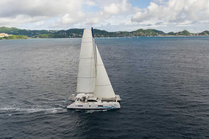 Inky Blue Yacht Photos Pics 2020 Outremer 51 catamaran sailing on open water with scenic island backdrop.
