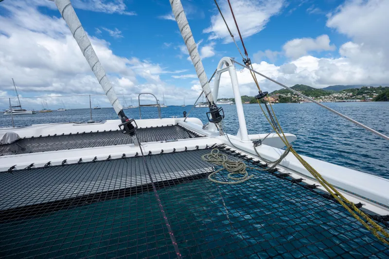 Inky Blue Yacht Photos Pics 2020 Outremer 51 catamaran on calm waters with scenic coastal view.