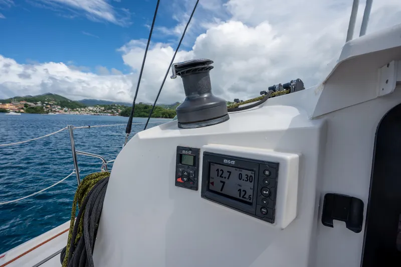 Inky Blue Yacht Photos Pics Outremer 51 sailboat cockpit with navigation display, ocean view, and lush coastline in the background.